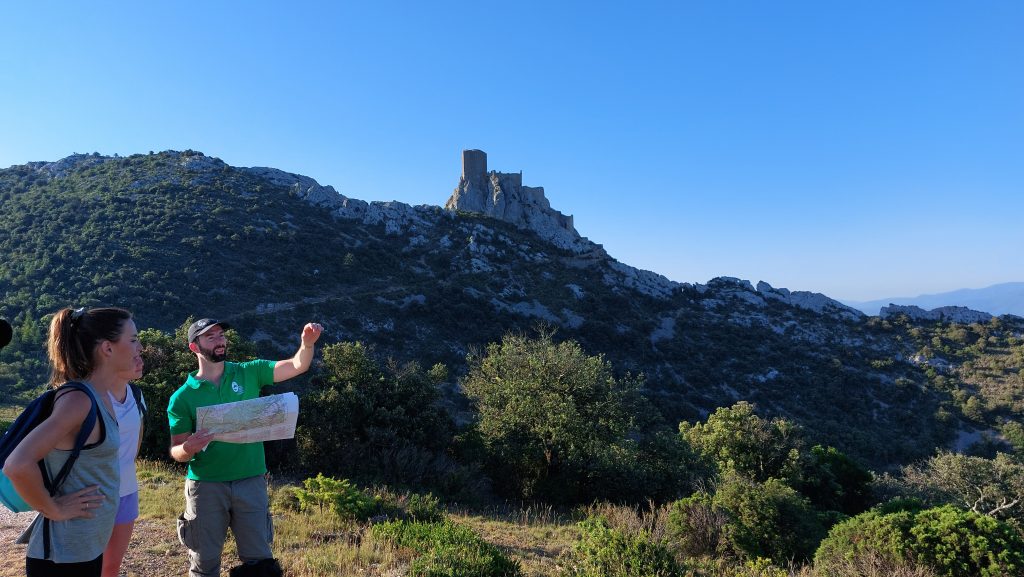 Château de Quéribus : un agent du Parc aide une touriste à se repérer en observant les reliefs du Parc naturel.